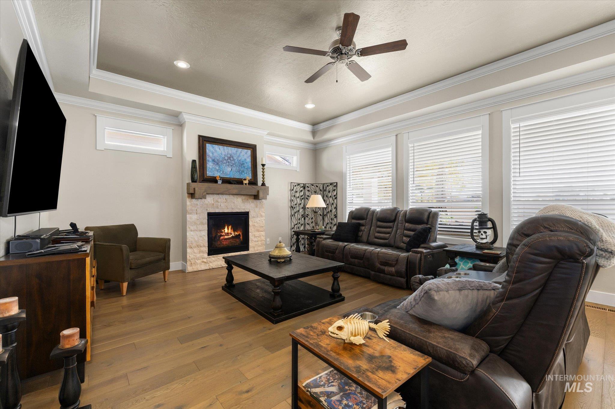 Living area featuring wood-type flooring, a ceiling fan, crown molding, a tray ceiling, and recessed lighting