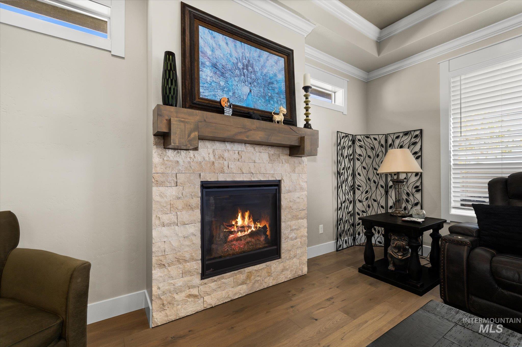 Sitting room featuring wood finished floors, crown molding, and a stone fireplace
