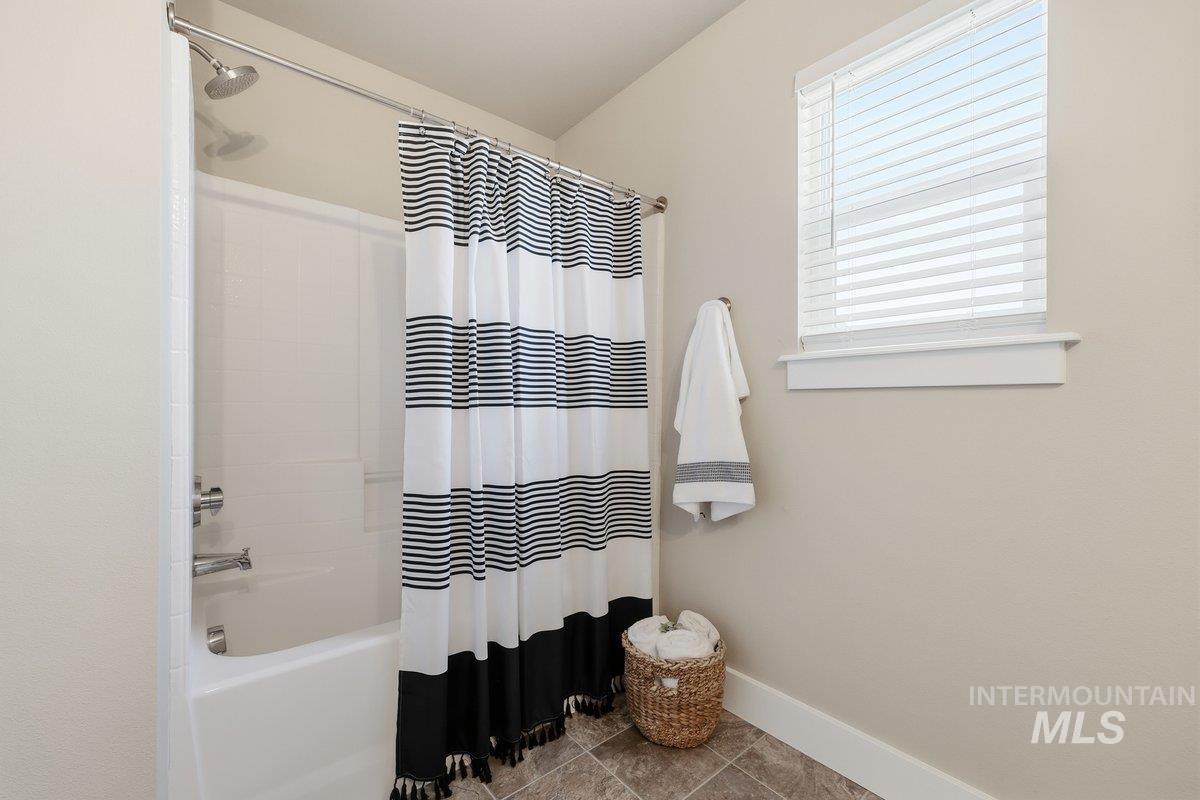Full bath featuring shower / bathtub combination with curtain and tile patterned flooring
