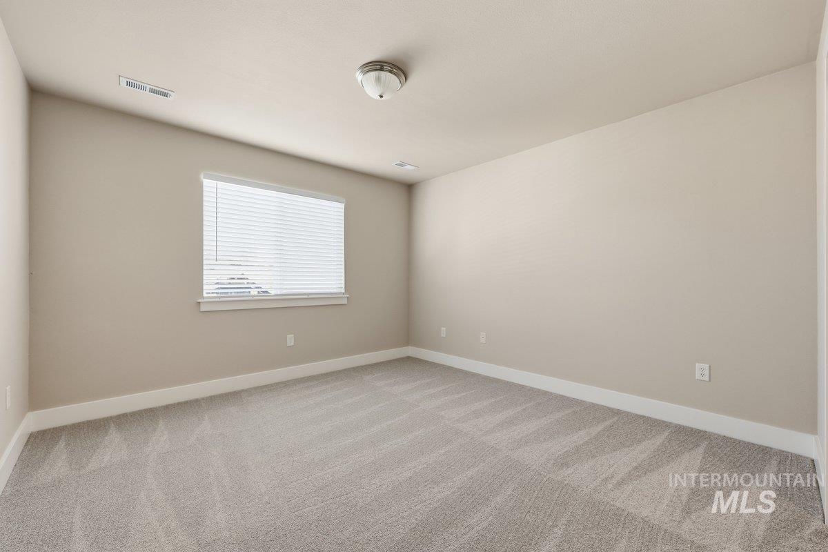 Spare room featuring light colored carpet and baseboards
