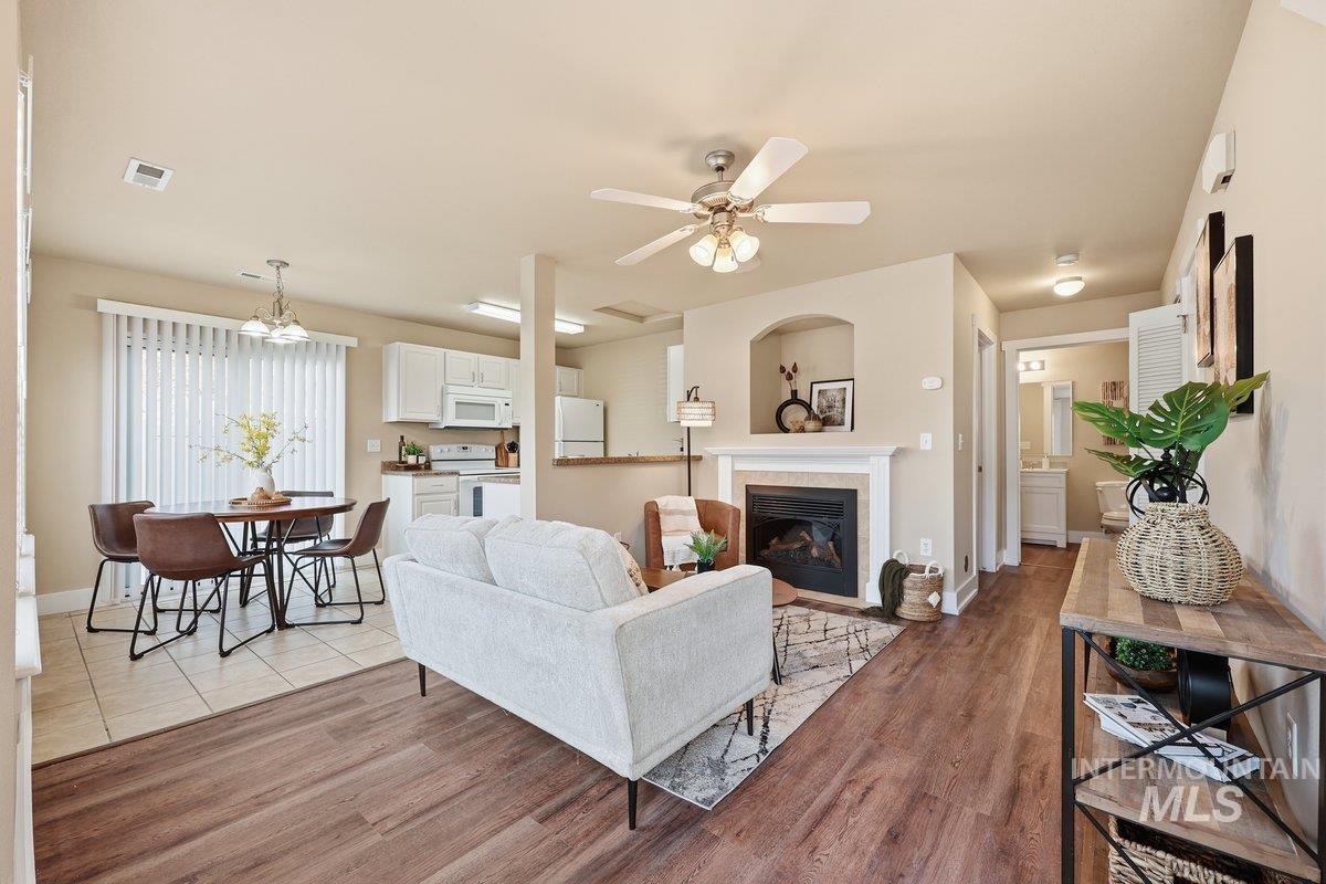 Living area with a ceiling fan, a fireplace with flush hearth, light wood-style flooring, and a chandelier