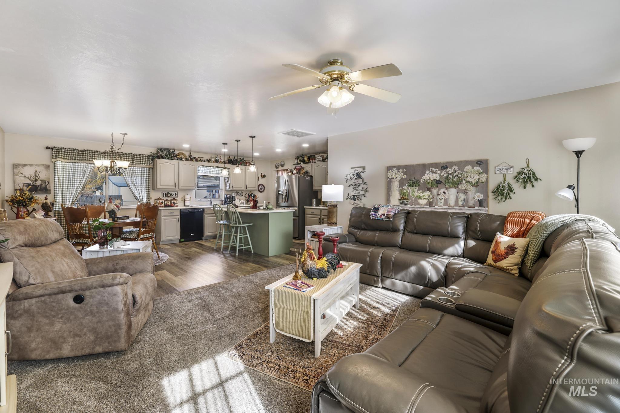 Living room featuring a ceiling fan, dark wood-style floors, and a chandelier