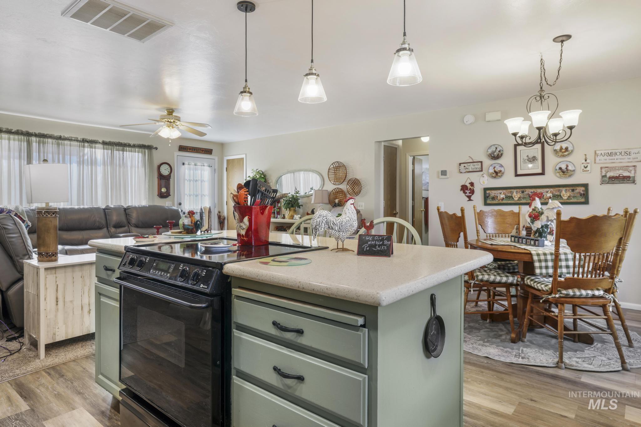 Kitchen with green cabinets, a center island, electric range, open floor plan, and light wood-style floors