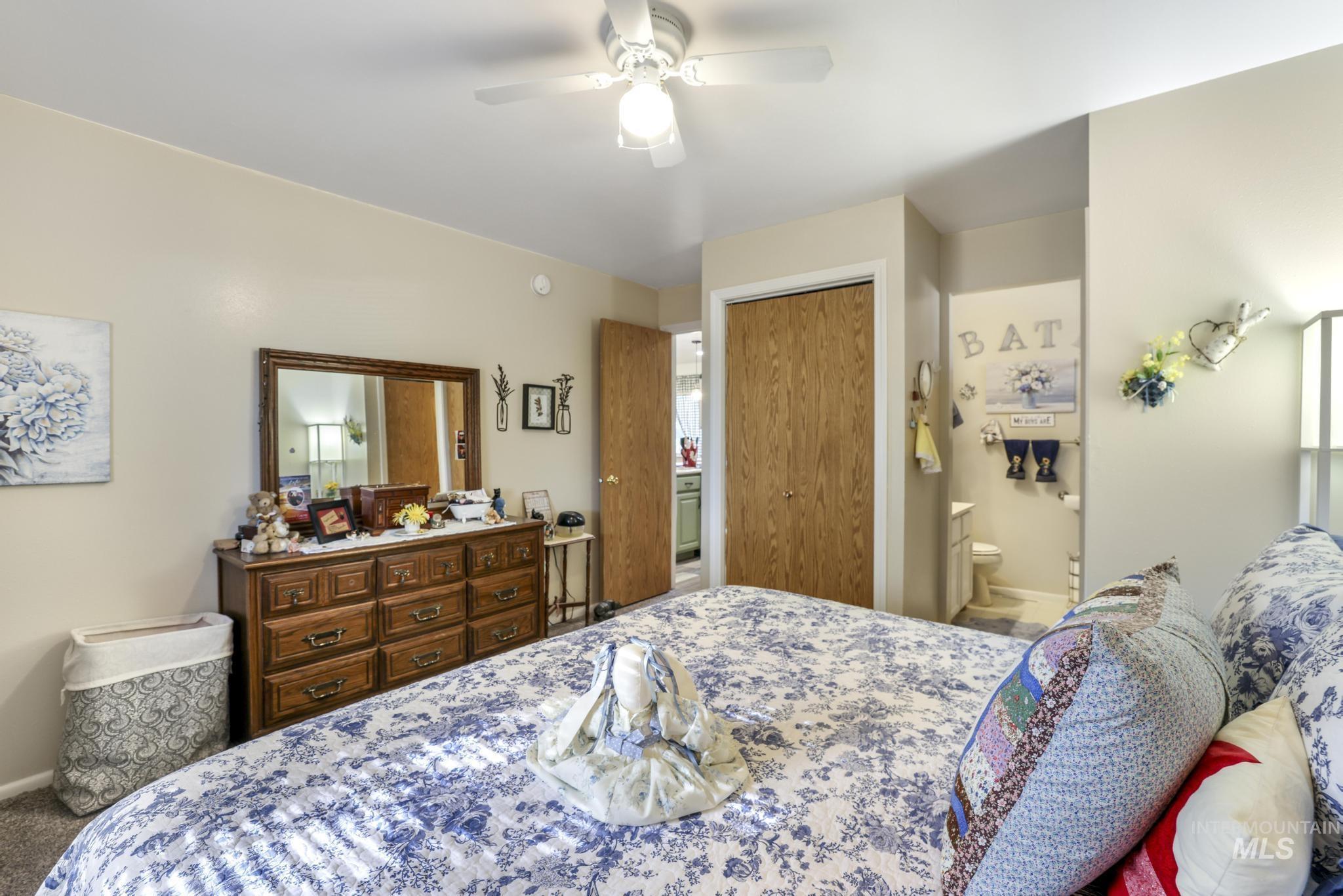 Carpeted bedroom featuring a closet, a ceiling fan, and ensuite bathroom