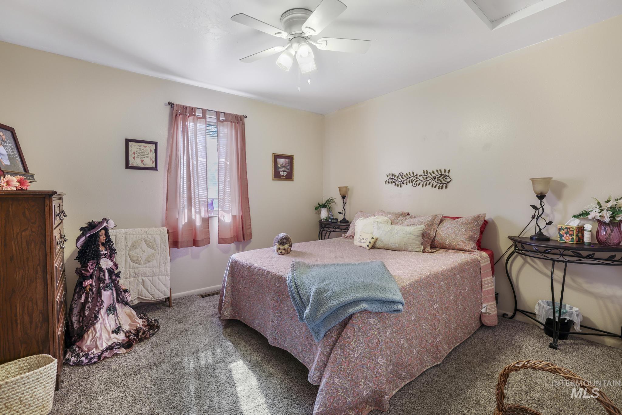 Carpeted bedroom with a ceiling fan
