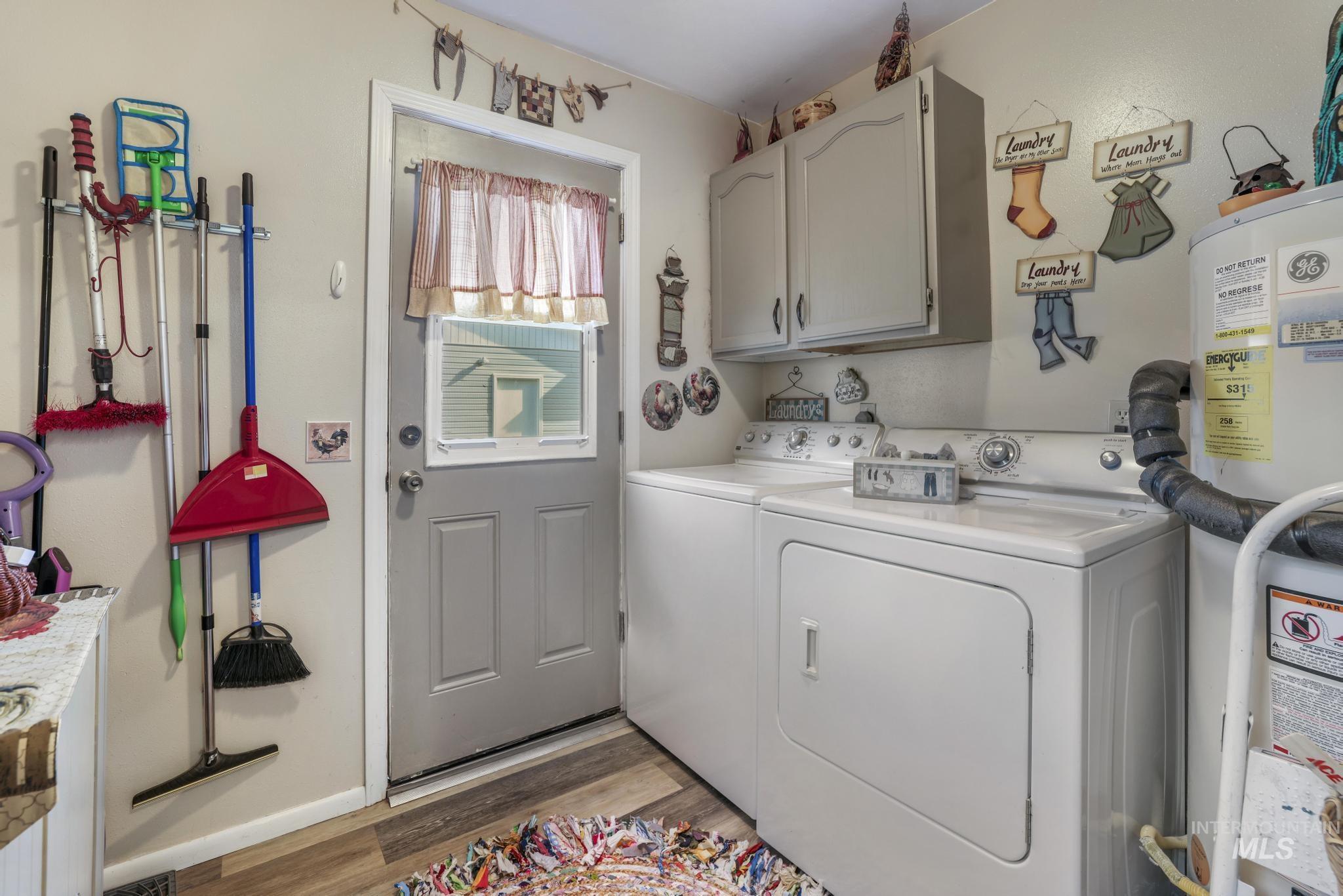 Laundry room featuring cabinet space, washing machine and clothes dryer, light wood-style flooring, and water heater