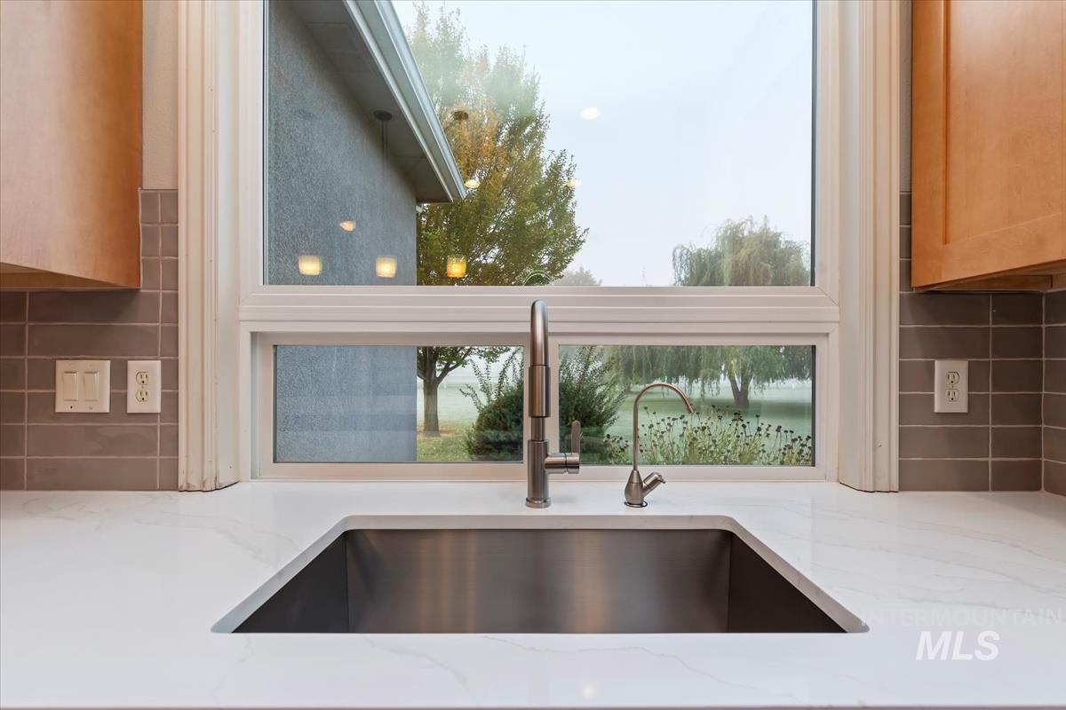 Kitchen view of light stone counters, backsplash, and brown cabinets