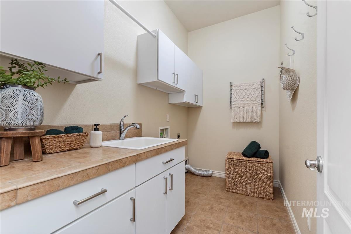Washroom featuring cabinet space, hookup for a washing machine, electric dryer hookup, and light tile patterned floors