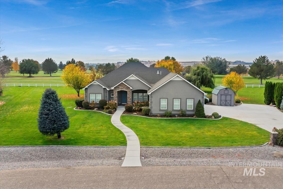 View of front of property with concrete driveway, stucco siding, and a shed