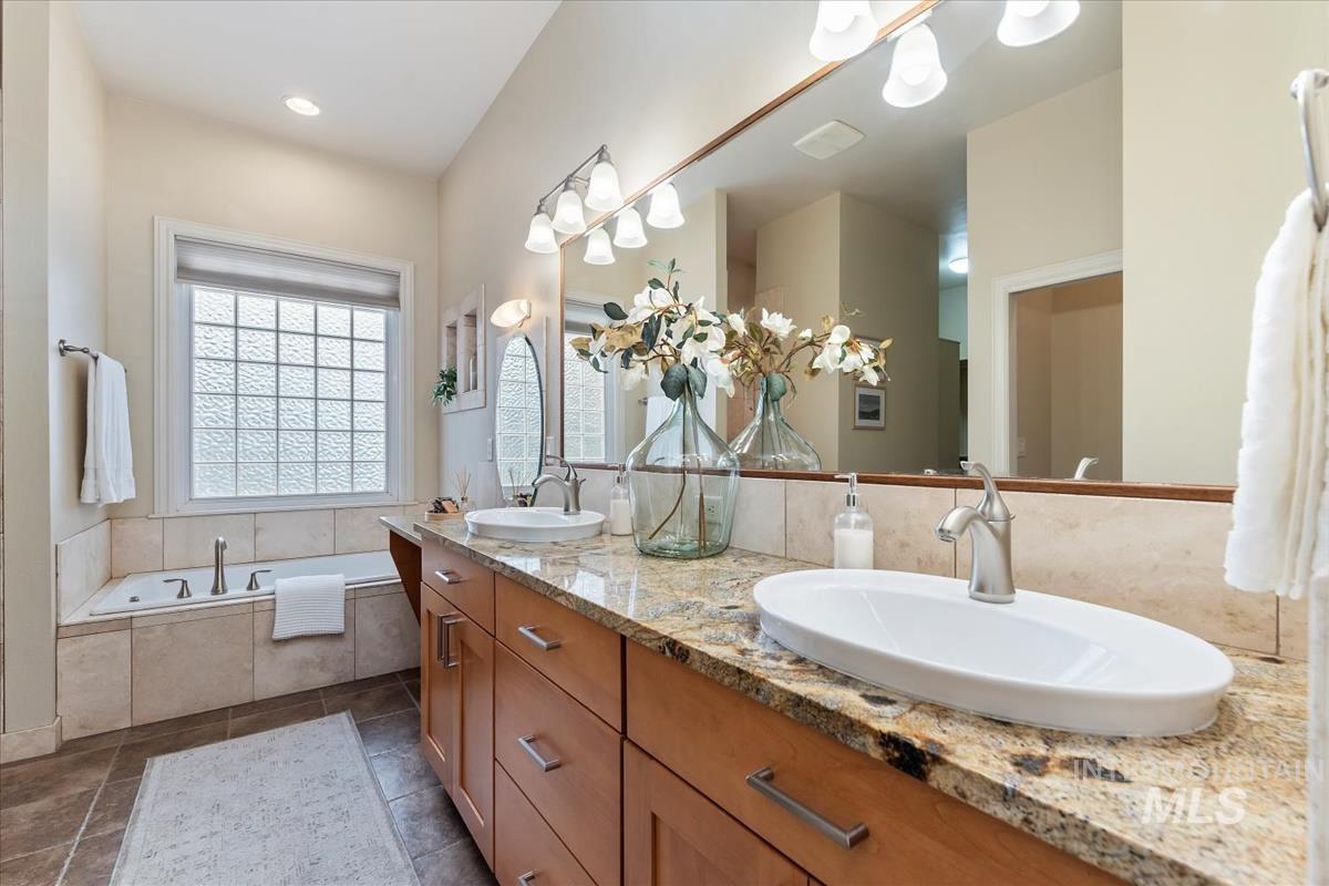 Full bathroom featuring double vanity, a garden tub, dark tile patterned flooring, and recessed lighting