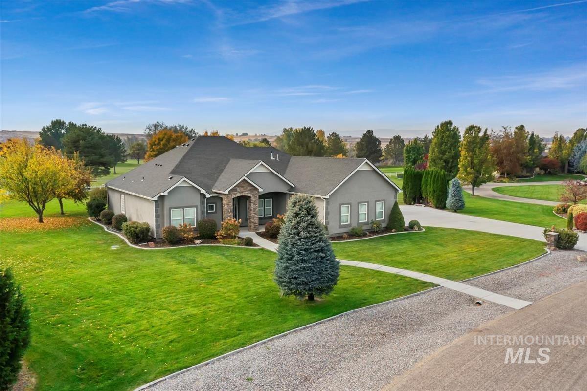 Ranch-style house with a front lawn, driveway, stone siding, and a shingled roof
