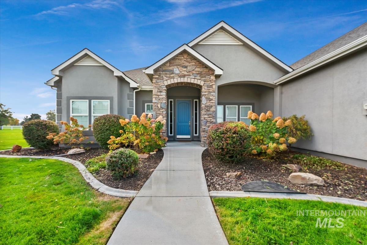 Doorway to property featuring stone siding, a yard, and stucco siding