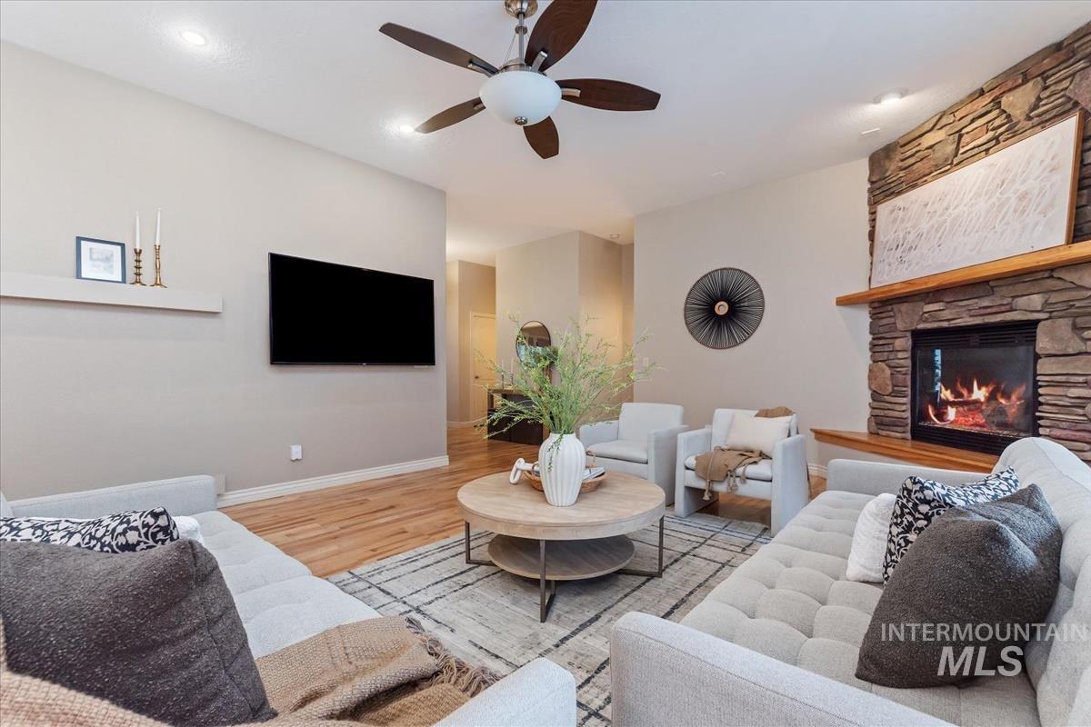Living room with wood finished floors, ceiling fan, and a fireplace