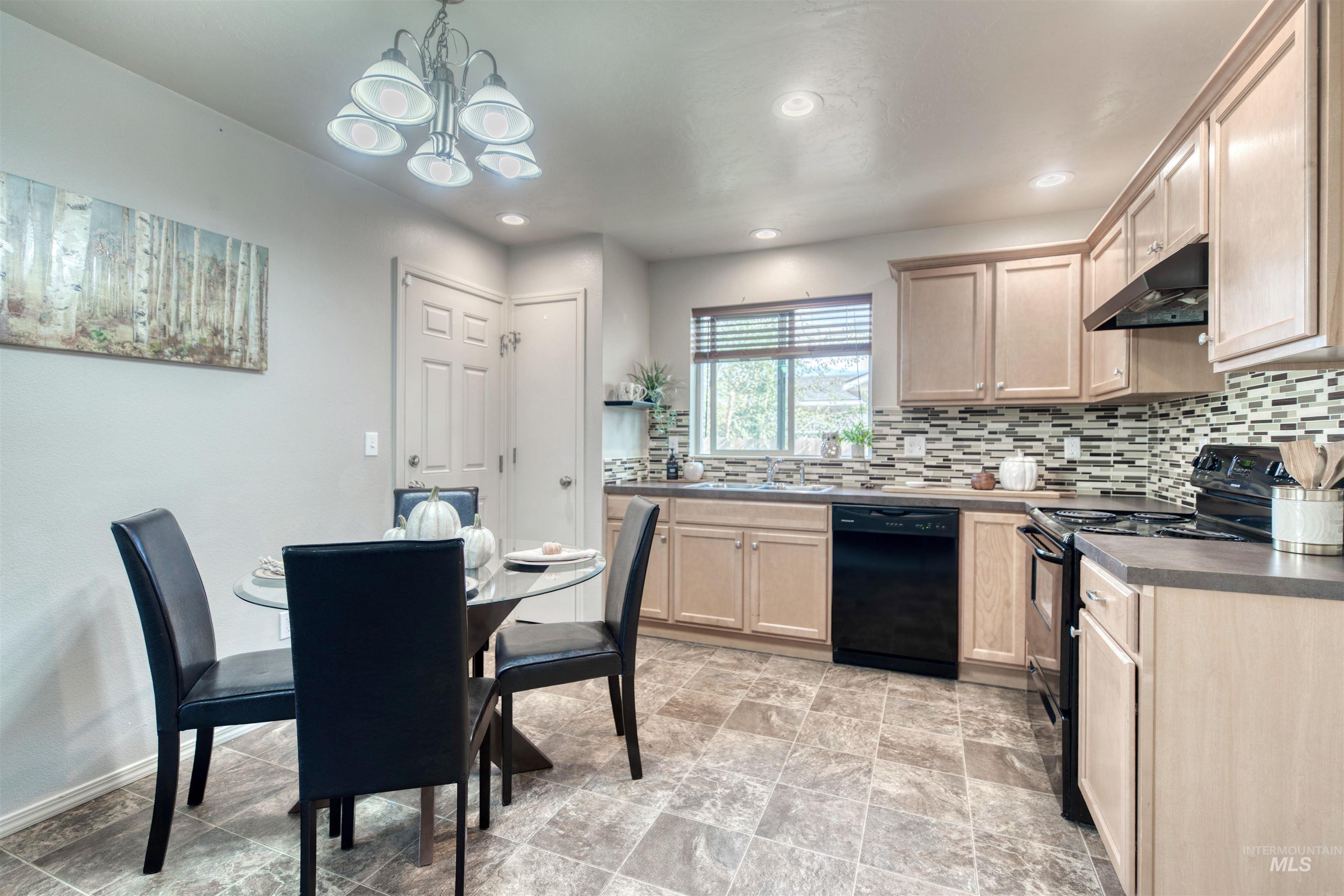 Kitchen with black appliances, decorative backsplash, under cabinet range hood, pendant lighting, and light brown cabinets