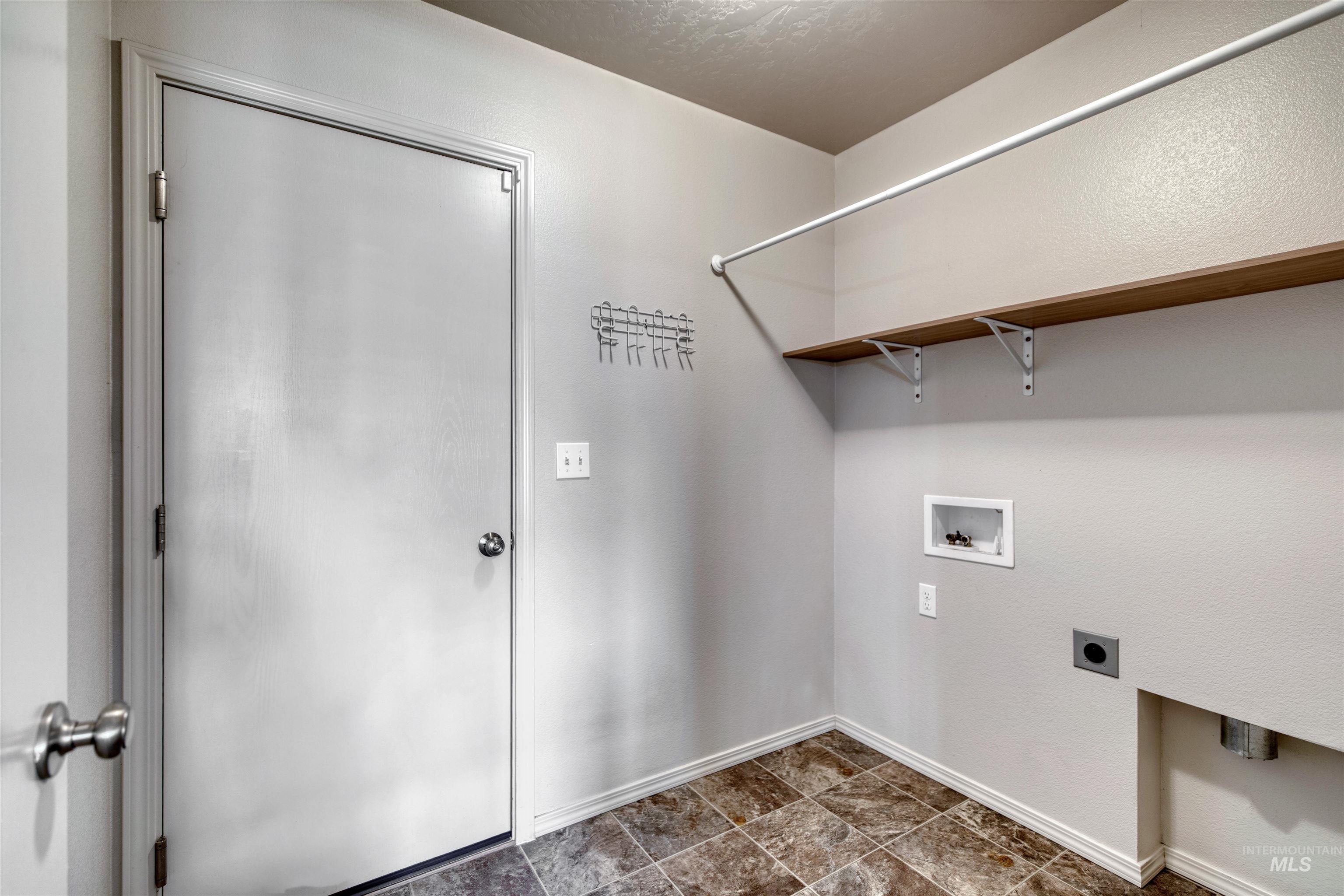 Washroom with hookup for a washing machine, electric dryer hookup, and stone finish floors
