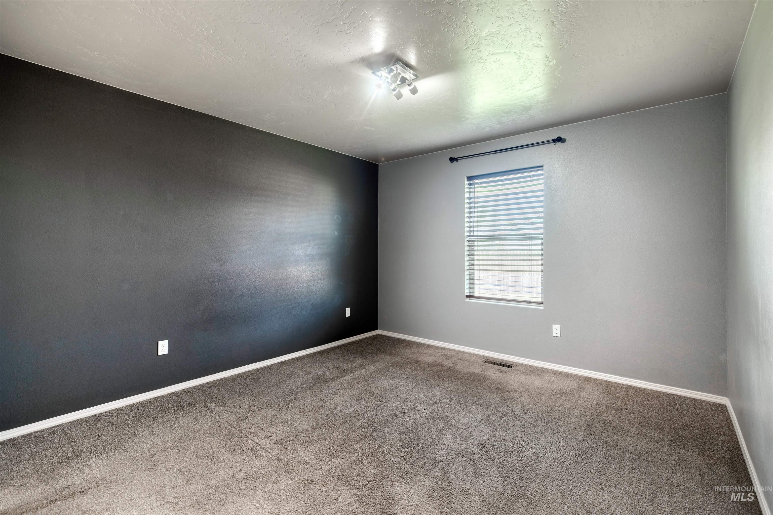 Unfurnished room with a textured ceiling and carpet flooring