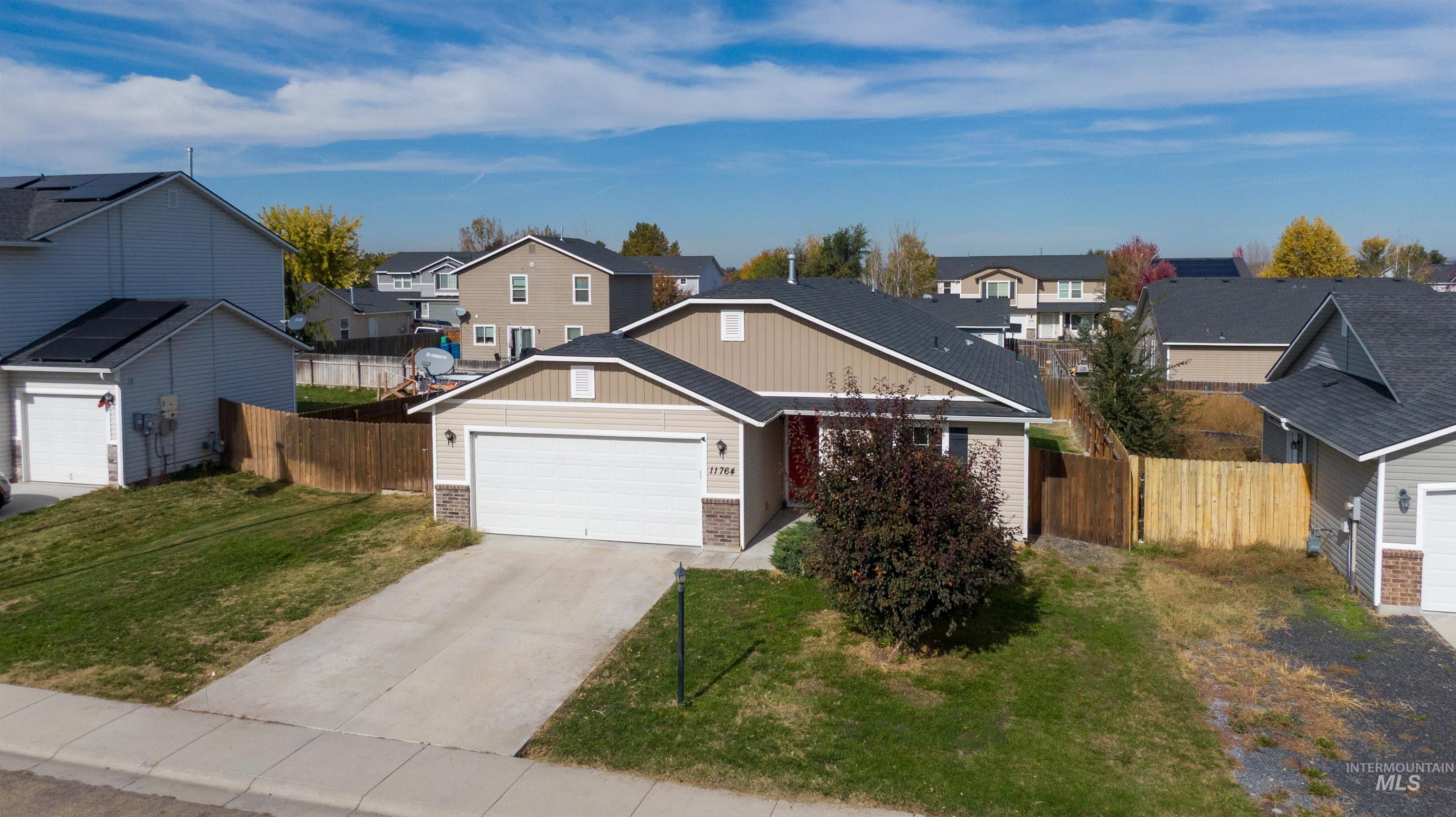 View of front of property with a residential view, brick siding, driveway, and a garage