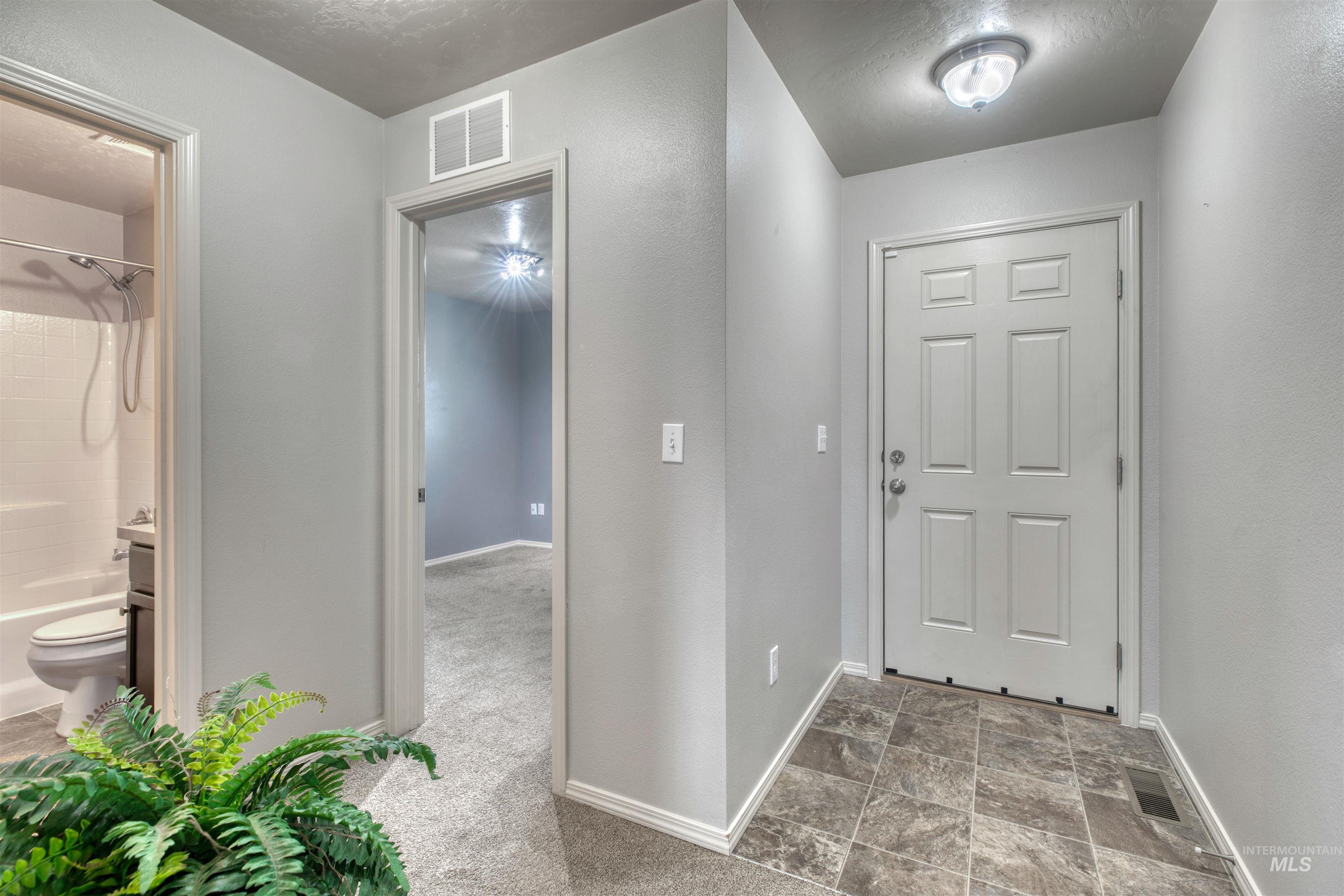 Carpeted entrance foyer with baseboards and stone finish flooring