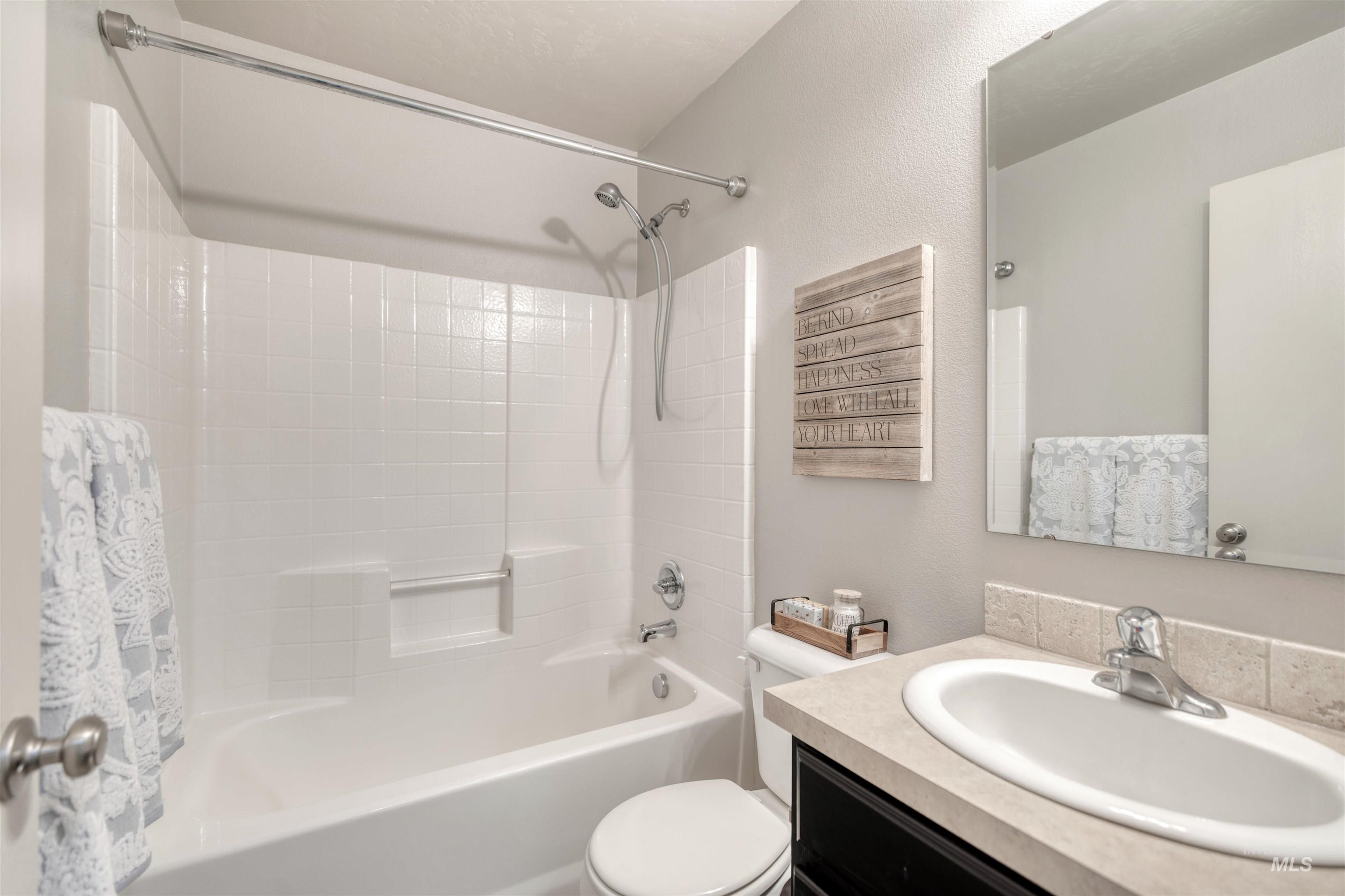 Full bathroom featuring vanity, shower / bath combo, and a textured wall
