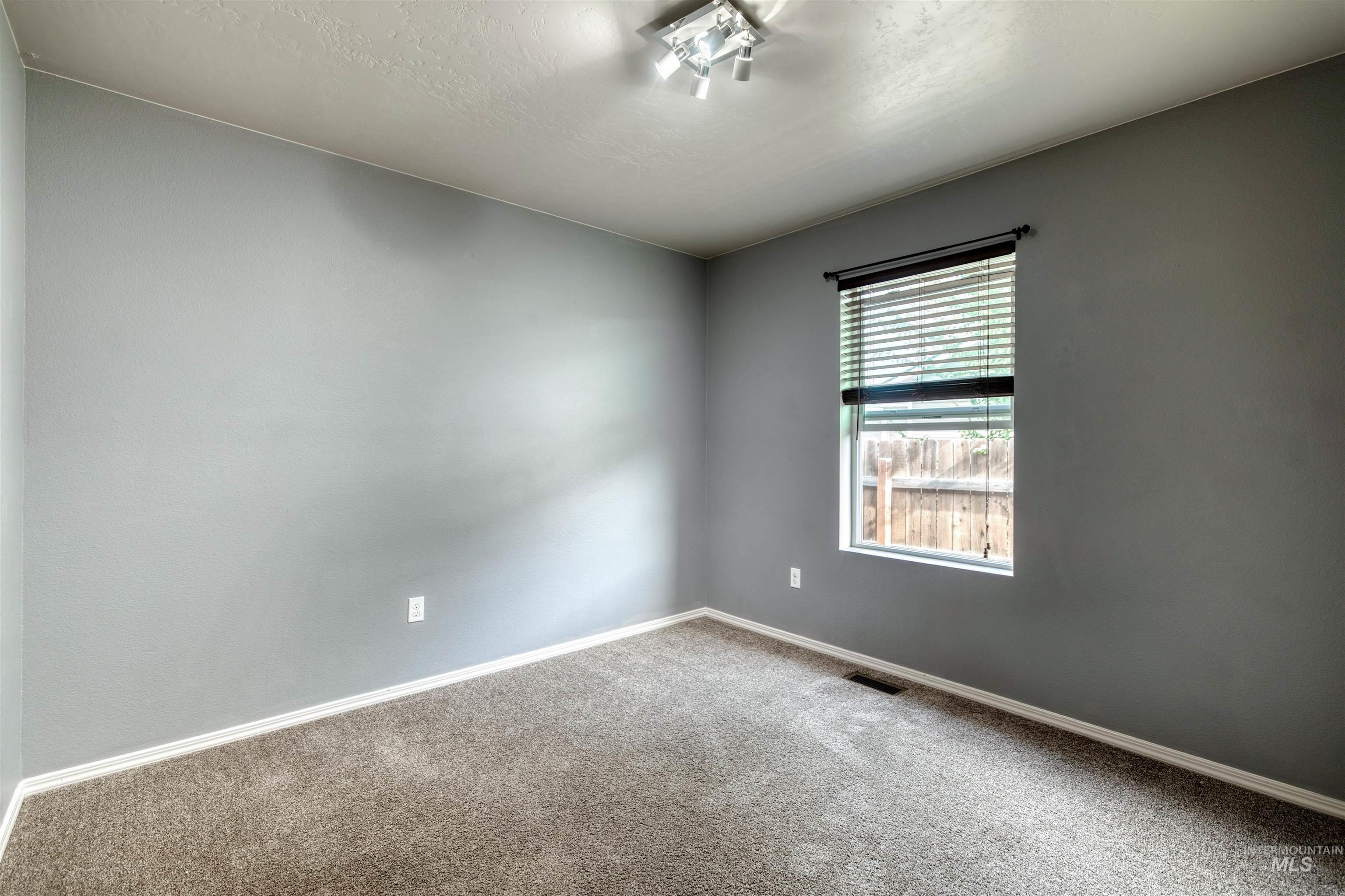 Carpeted spare room featuring baseboards and a textured ceiling