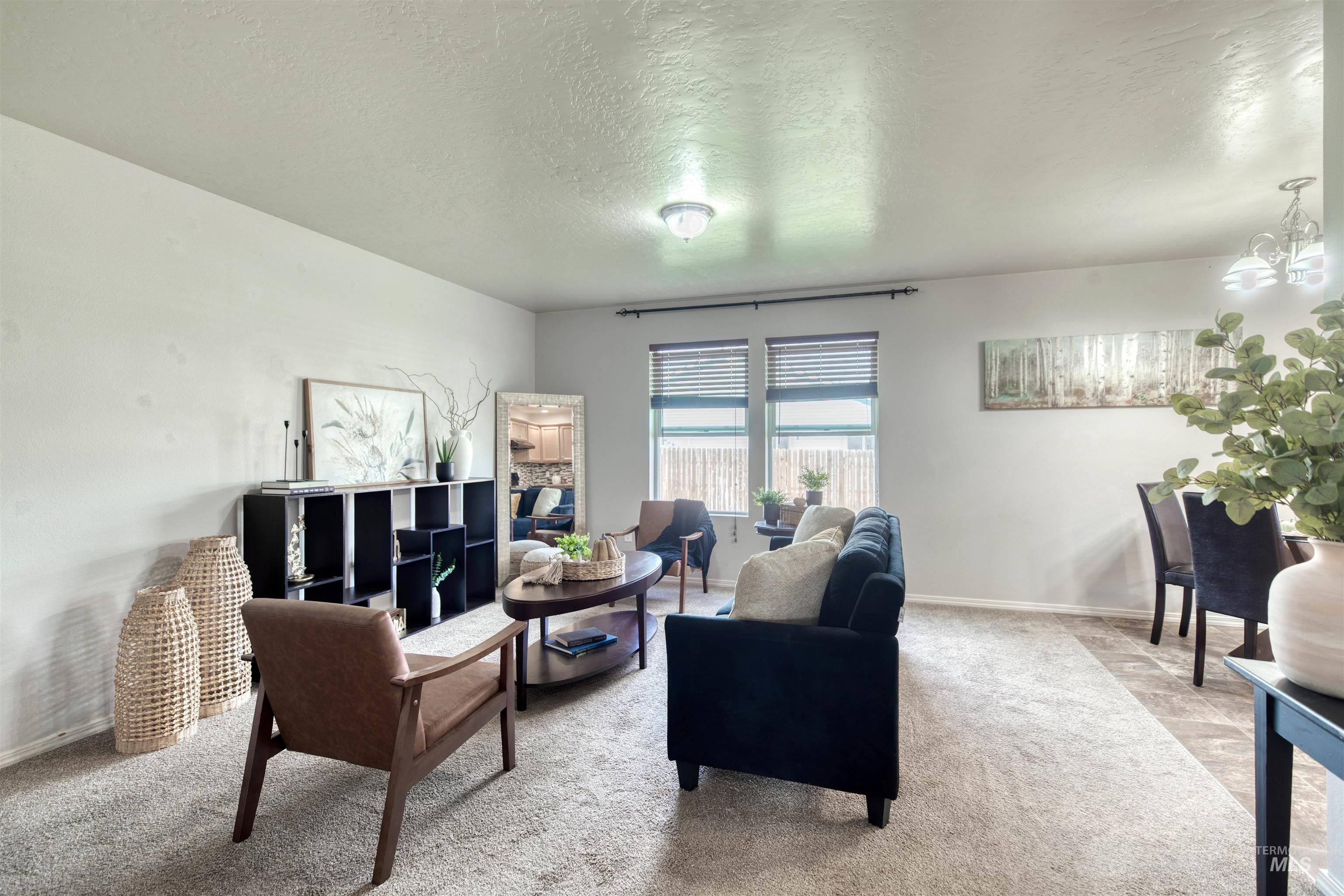 Carpeted living area with a textured ceiling and a chandelier