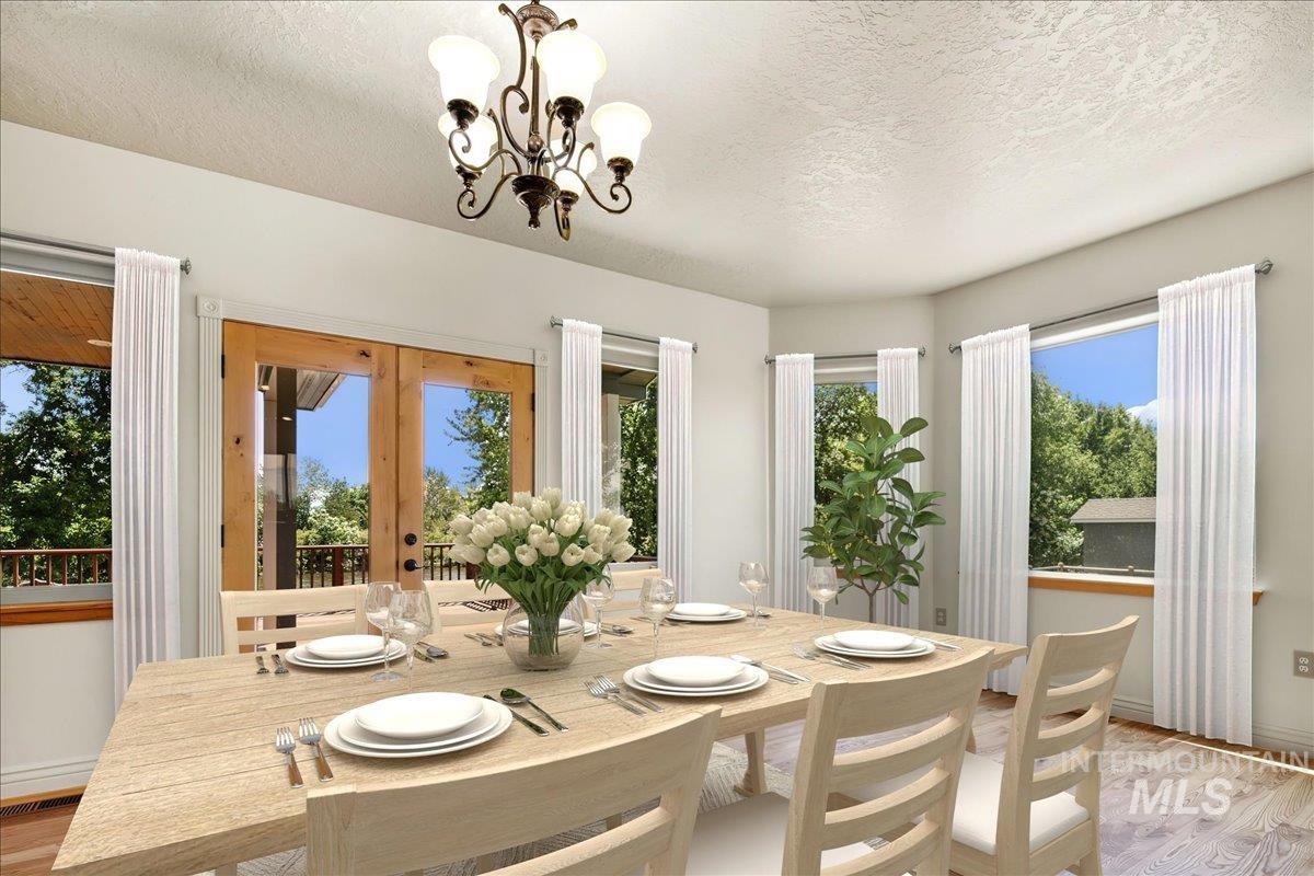Dining space with light wood-style floors, a textured ceiling, french doors, and a chandelier