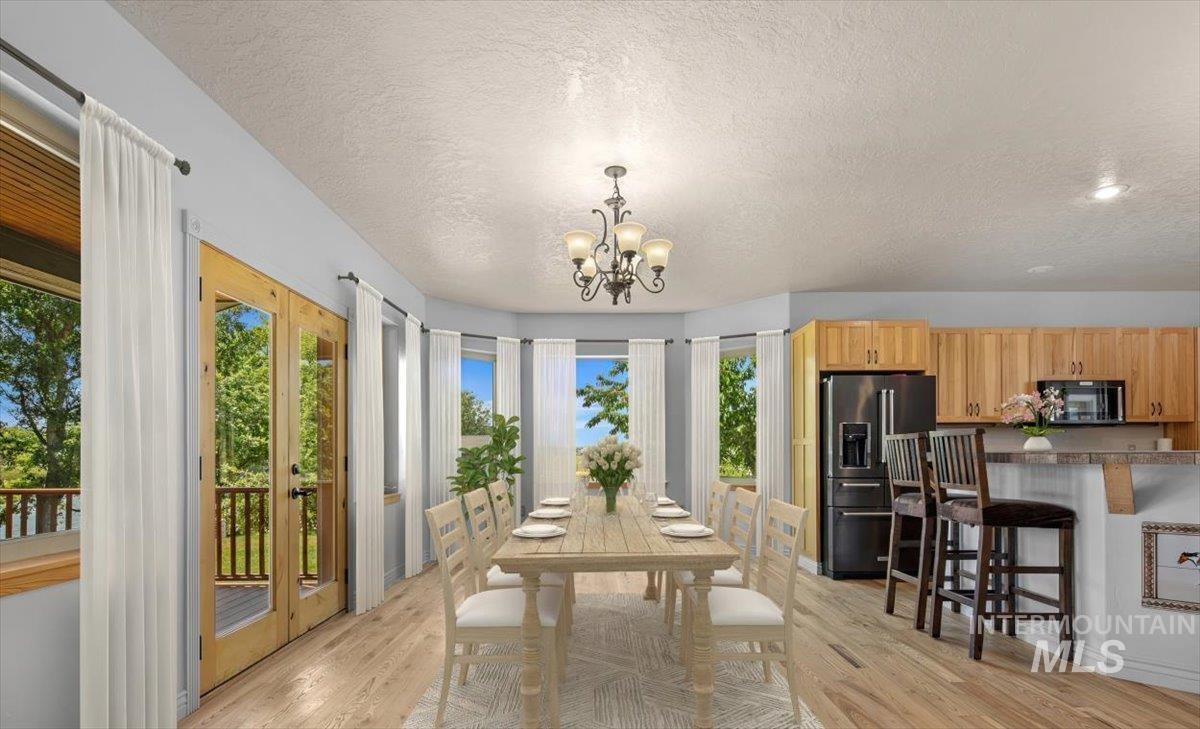 Dining room with a textured ceiling, a chandelier, and light wood-type flooring