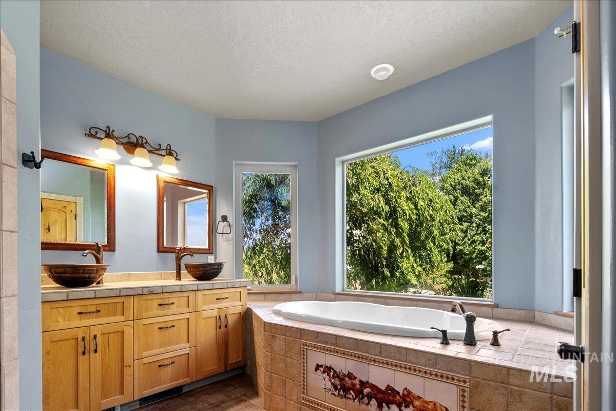 Full bathroom with double vanity, a bath, and a textured ceiling