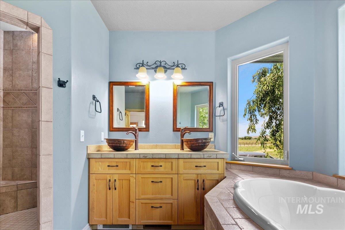 Bathroom with a garden tub, vanity, and tiled shower