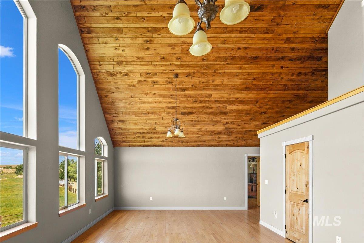 Unfurnished living room with high vaulted ceiling, wooden ceiling, and light wood-style flooring