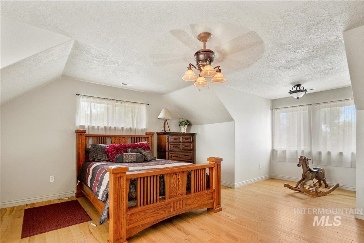 Bedroom featuring wood finished floors, a textured ceiling, and vaulted ceiling