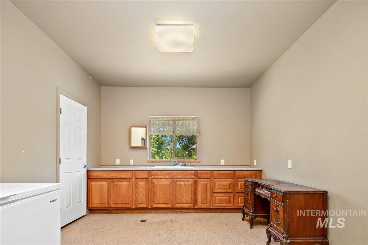 Home office with light carpet and a sink