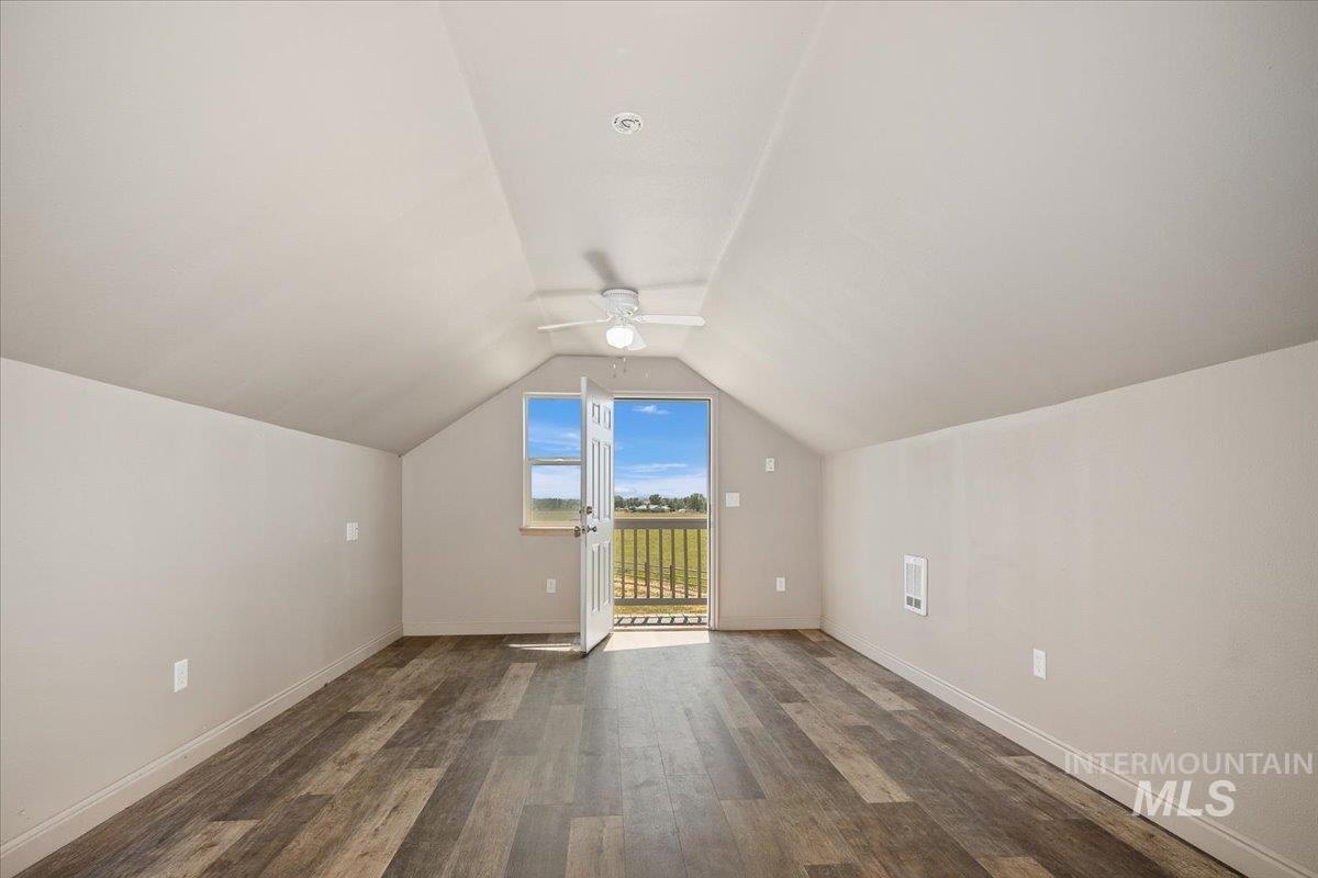 Bonus room featuring ceiling fan, dark wood-style flooring, and vaulted ceiling