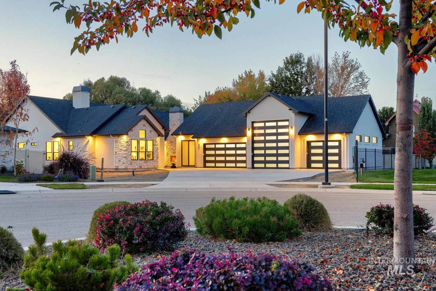 View of front of house with driveway, a chimney, a garage, and stone siding