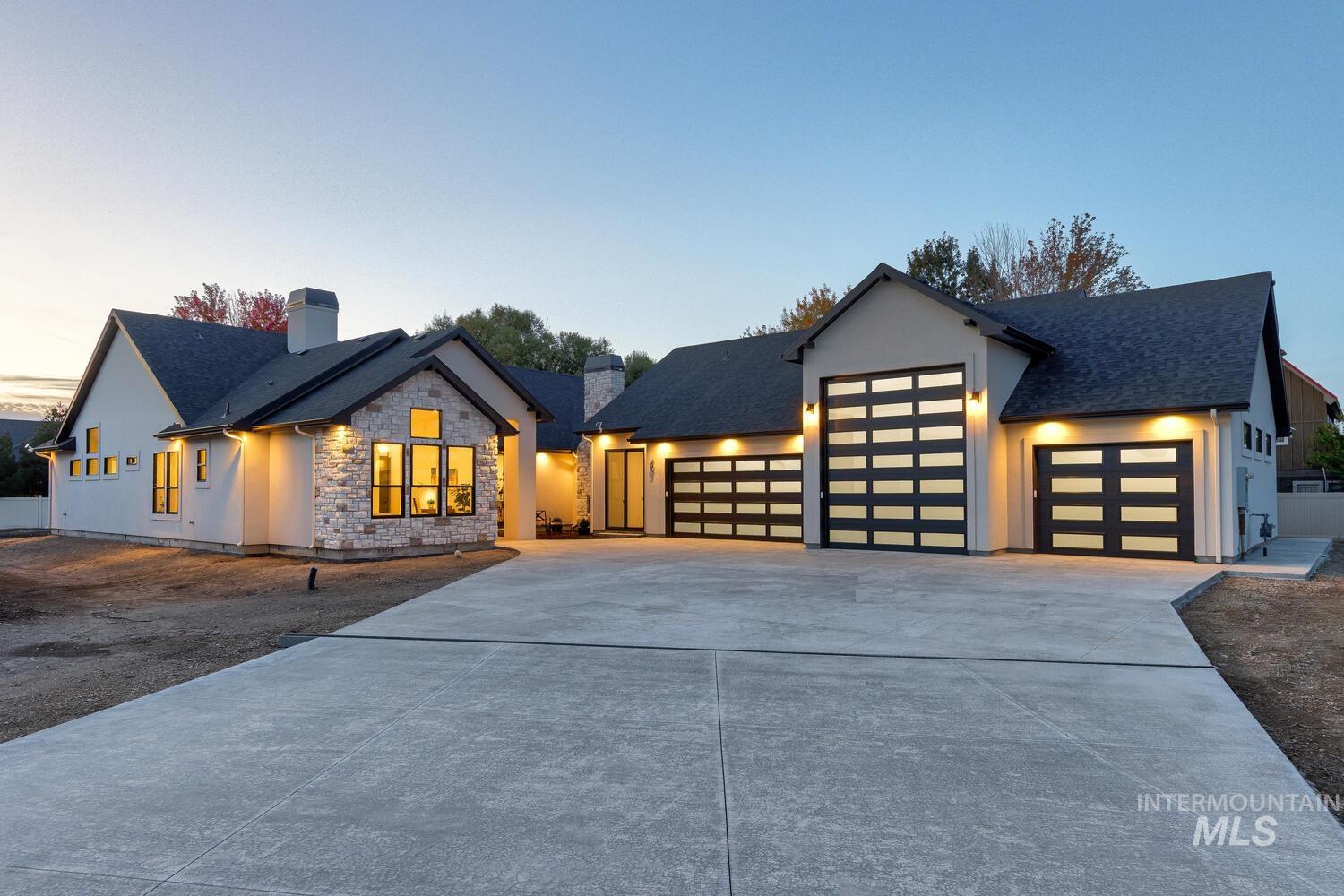 View of front facade featuring concrete driveway, stone siding, an attached garage, a chimney, and stucco siding