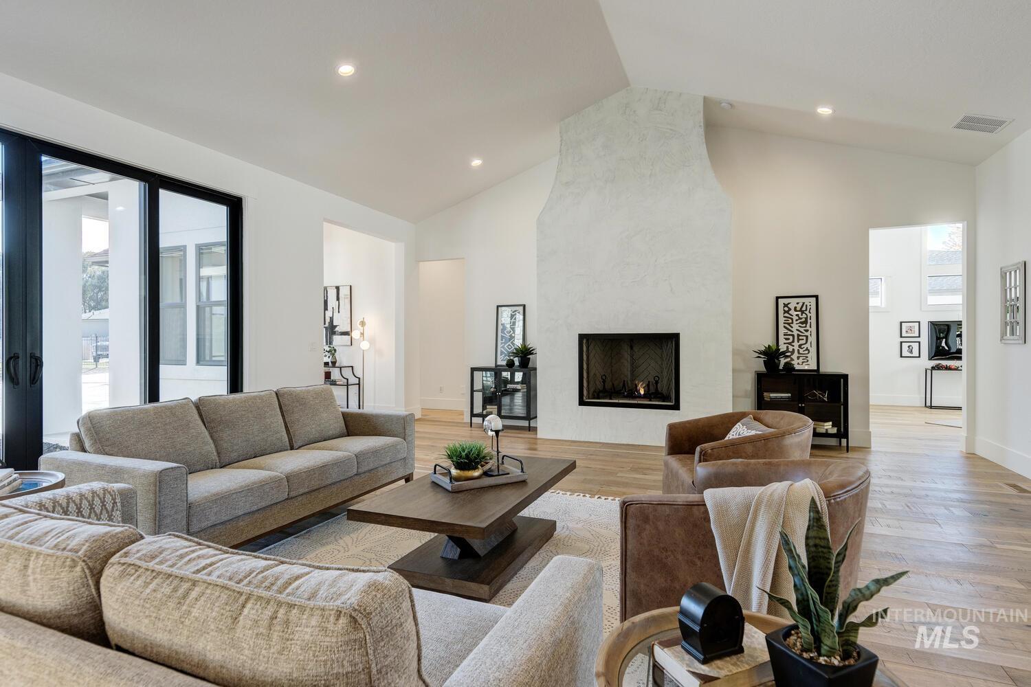 Living room with light wood-style floors, healthy amount of natural light, high vaulted ceiling, a fireplace, and recessed lighting