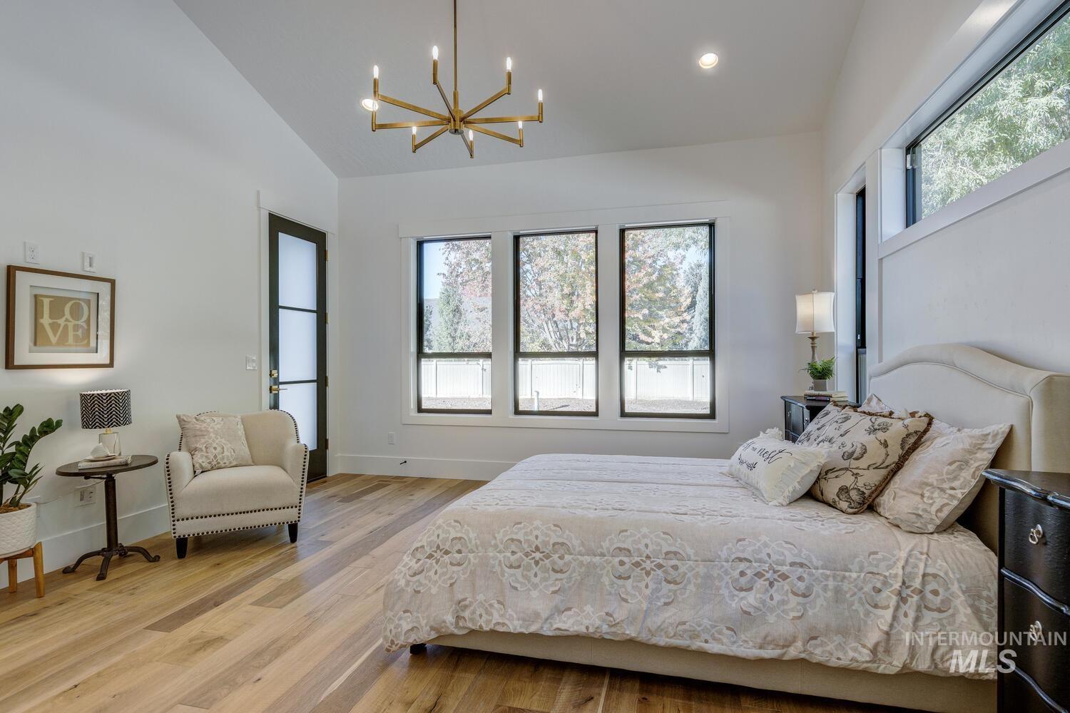 Bedroom with light wood finished floors, a chandelier, recessed lighting, and high vaulted ceiling