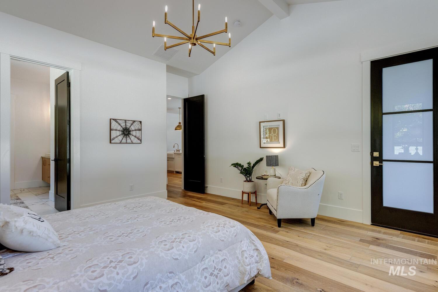 Bedroom with light wood-style floors, a chandelier, beamed ceiling, and high vaulted ceiling