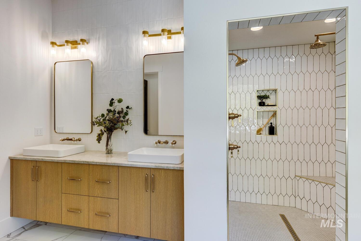 Full bathroom with double vanity, light tile patterned floors, a walk in shower, and tile walls