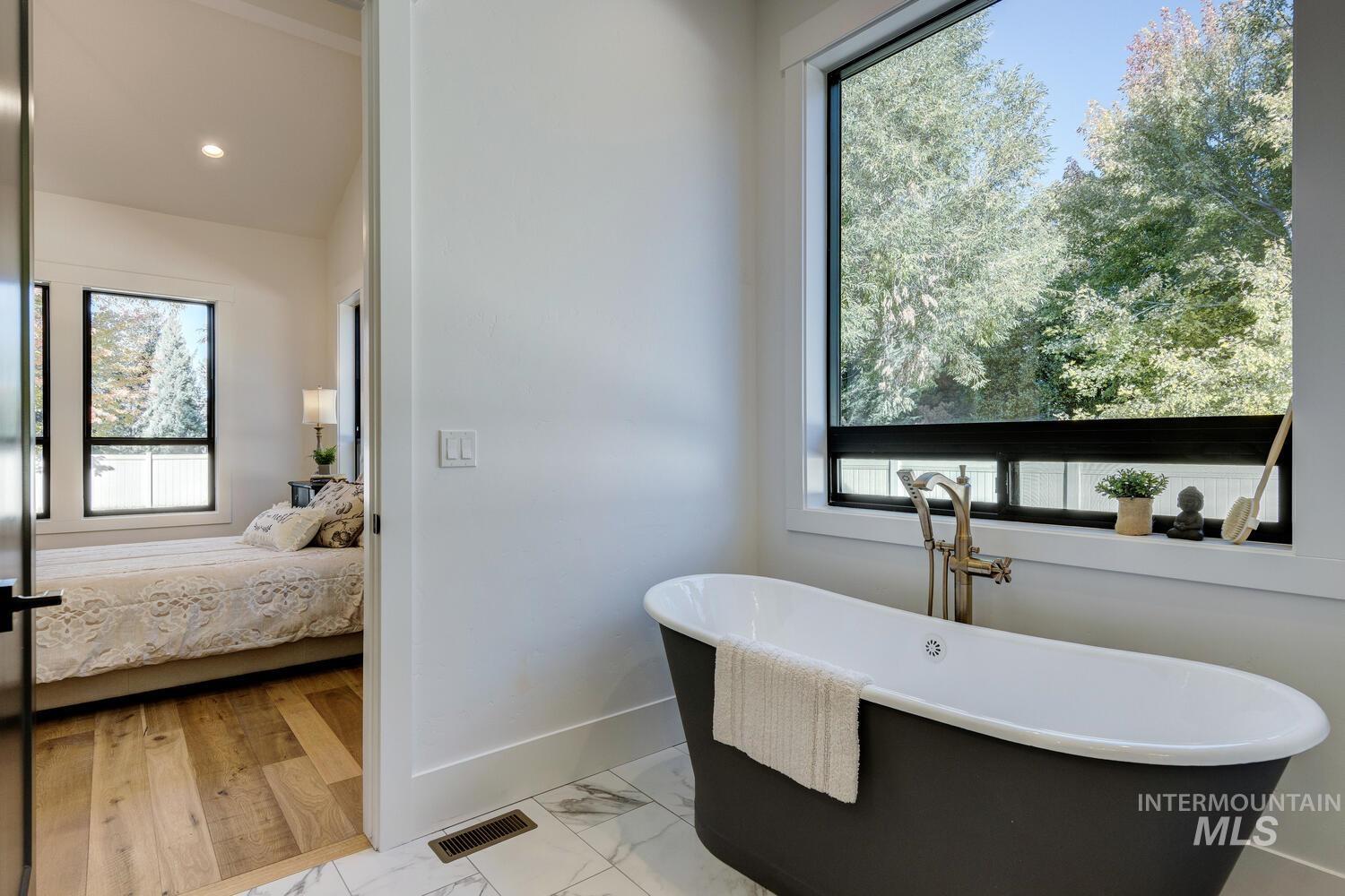 Ensuite bathroom with marble look tiles, a soaking tub, and recessed lighting