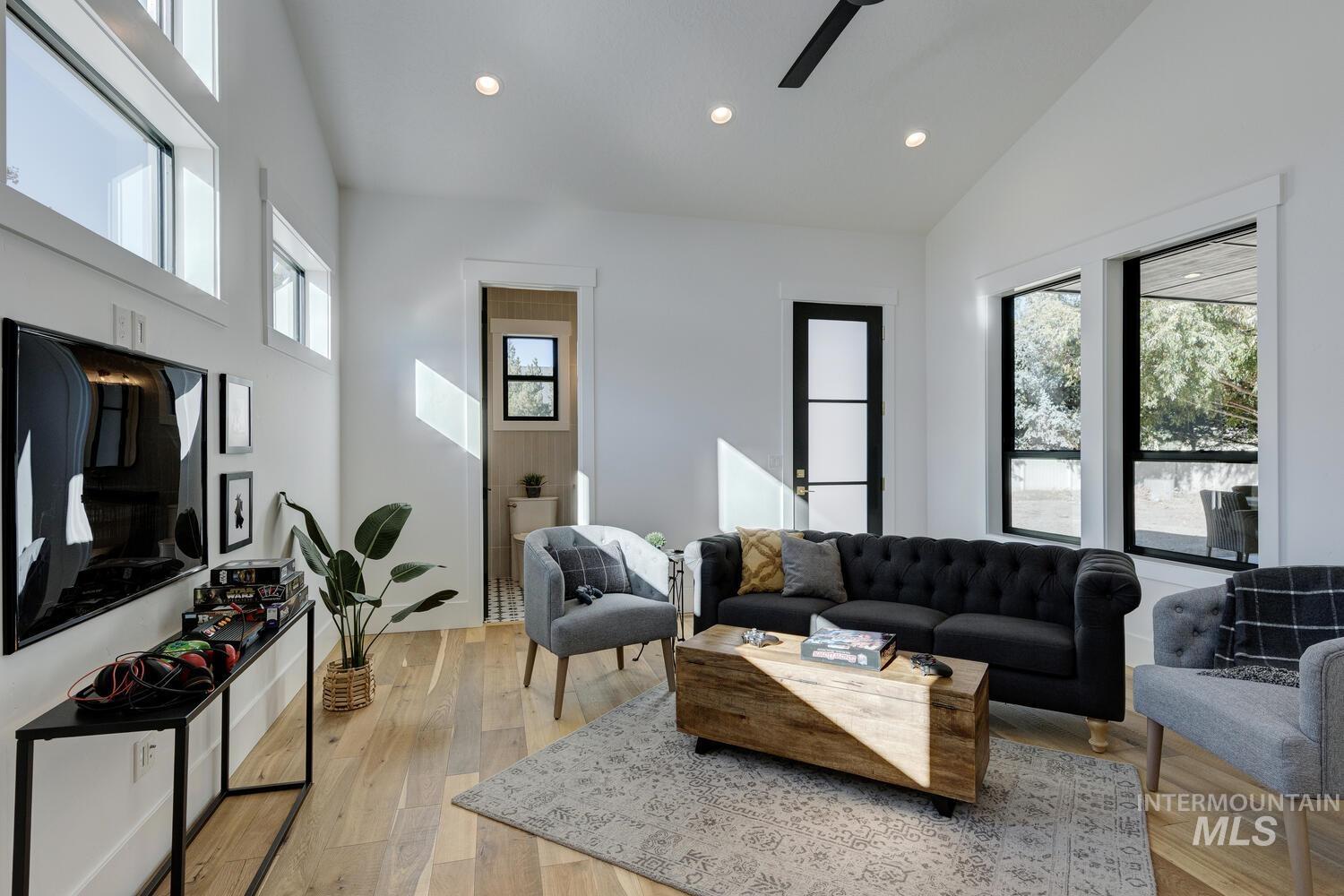 Living room with recessed lighting, light wood-type flooring, high vaulted ceiling, and a ceiling fan