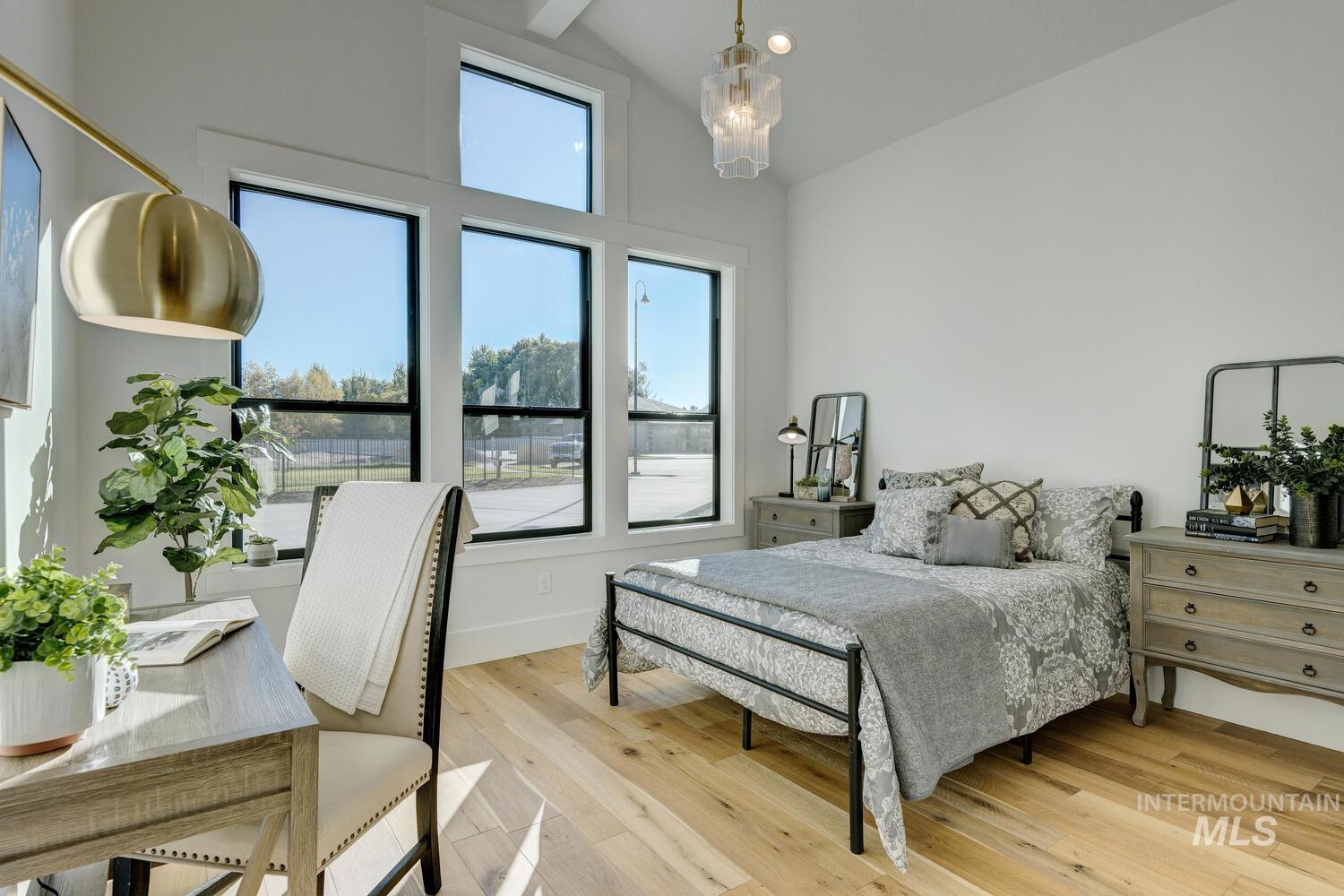 Bedroom featuring light wood-style floors, high vaulted ceiling, and beam ceiling