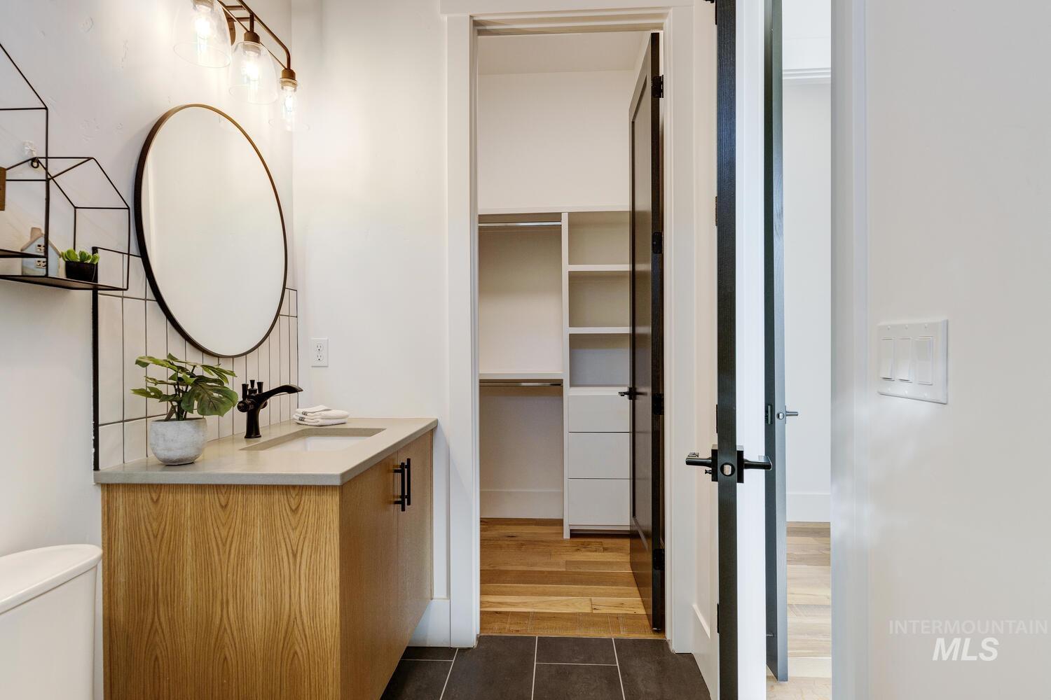 Half bathroom with vanity, dark tile patterned floors, and a spacious closet