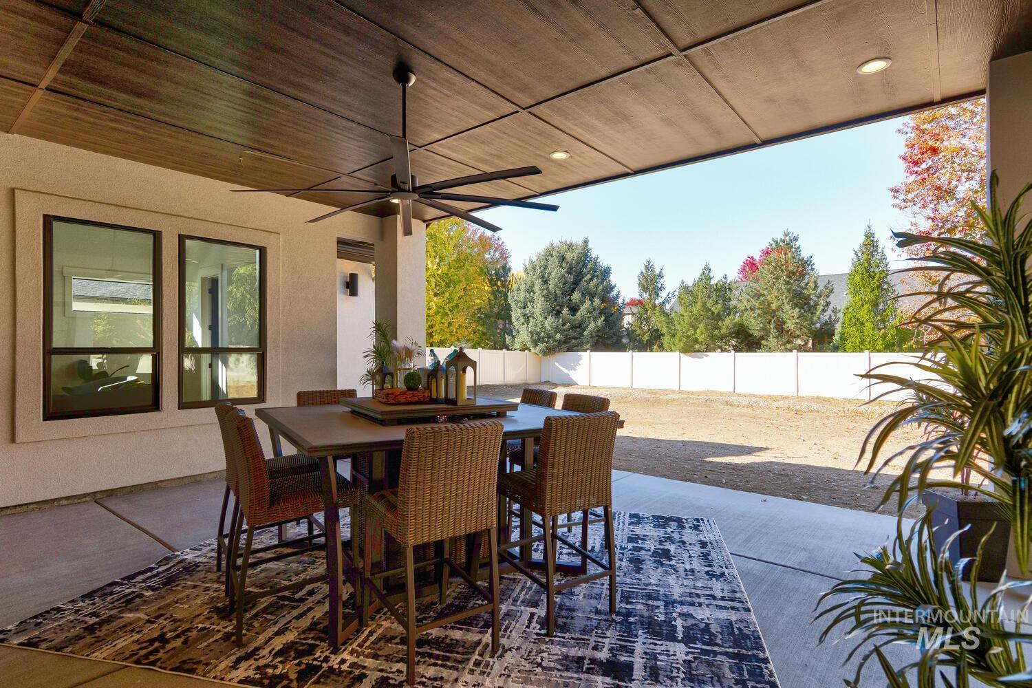 Fenced backyard with ceiling fan, outdoor dining space, and a patio area