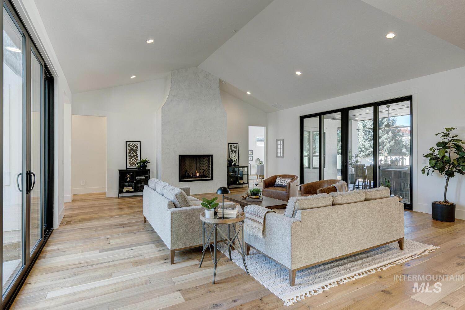 Living area featuring high vaulted ceiling, a large fireplace, light wood-type flooring, and recessed lighting