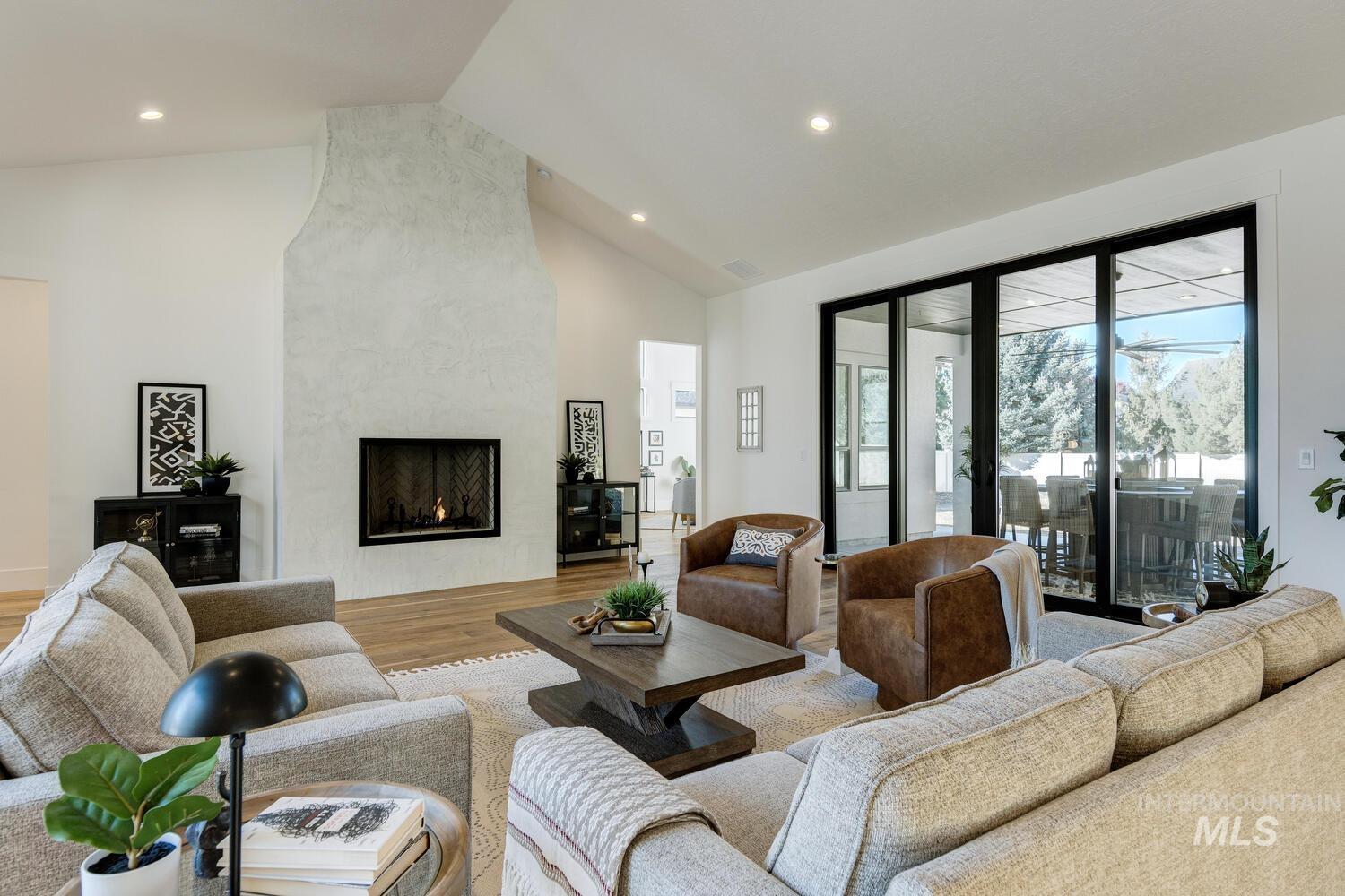 Living room featuring high vaulted ceiling, a high end fireplace, wood finished floors, and recessed lighting