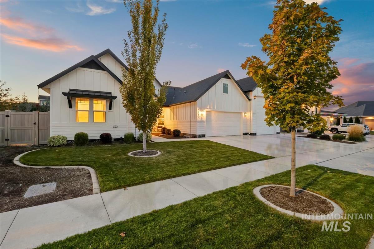 Modern farmhouse featuring board and batten siding, a gate, concrete driveway, and a garage