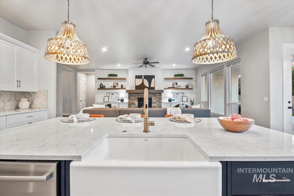 Kitchen with light stone counters, open floor plan, decorative light fixtures, a ceiling fan, and recessed lighting