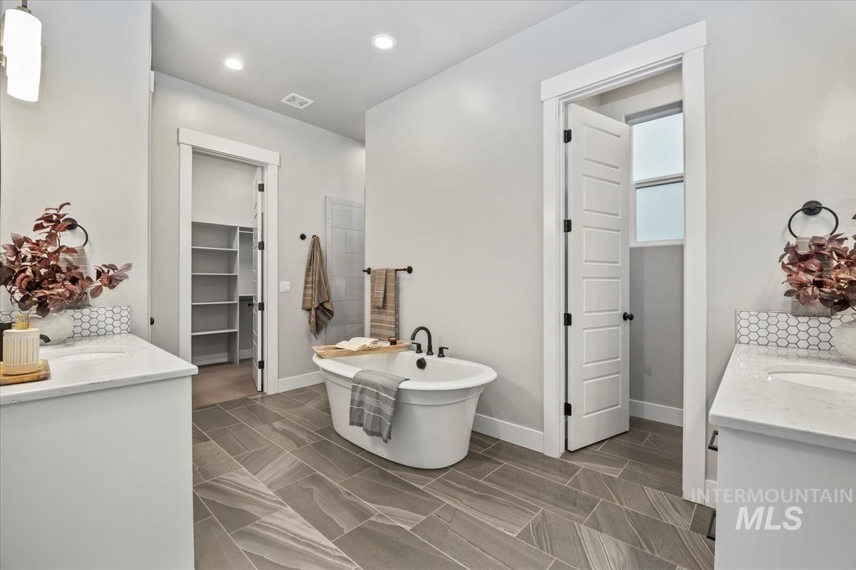 Bathroom with vanity, a spacious closet, a freestanding bath, and recessed lighting