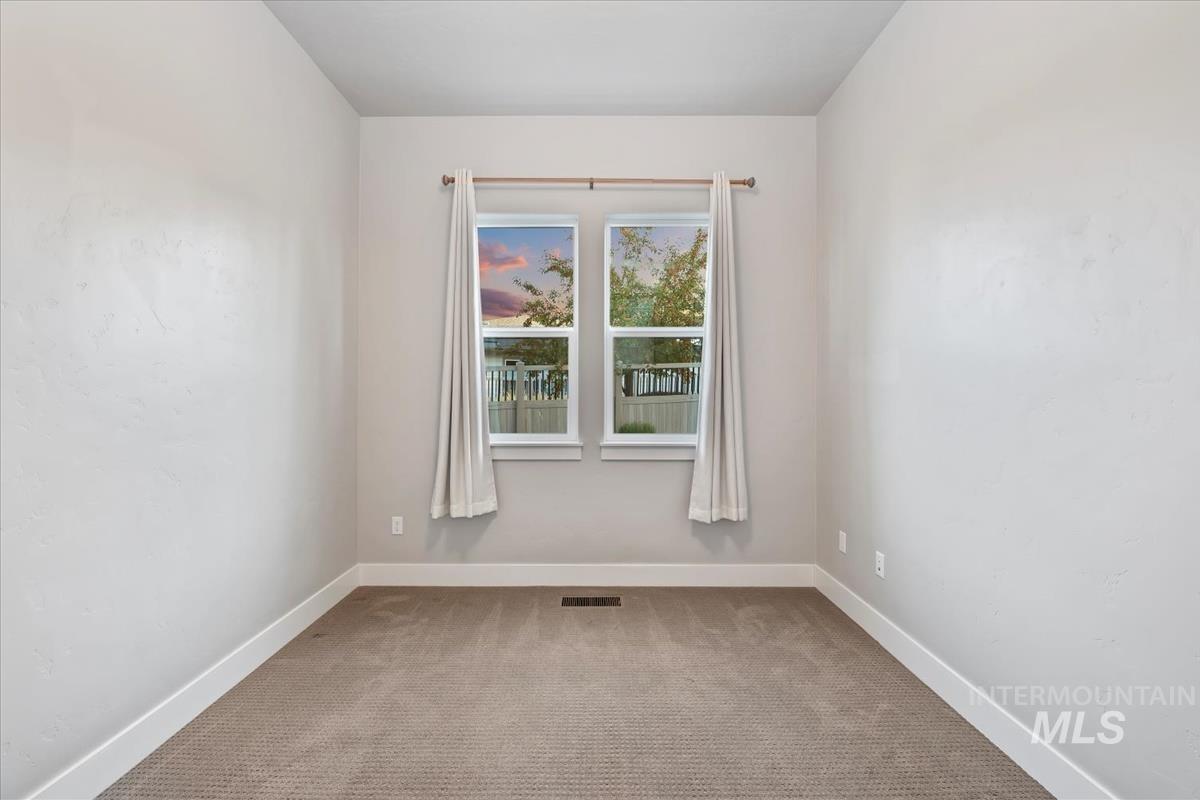 Carpeted spare room featuring baseboards